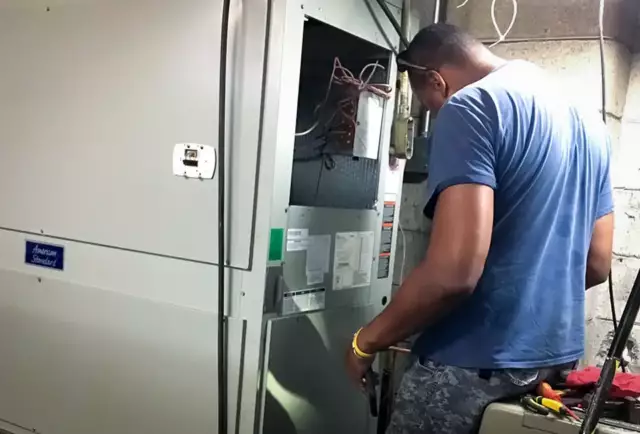 Owner of Nichols & Sons HVAC, Tyrone Nichols, performs maintenance on a customer's air handler.
